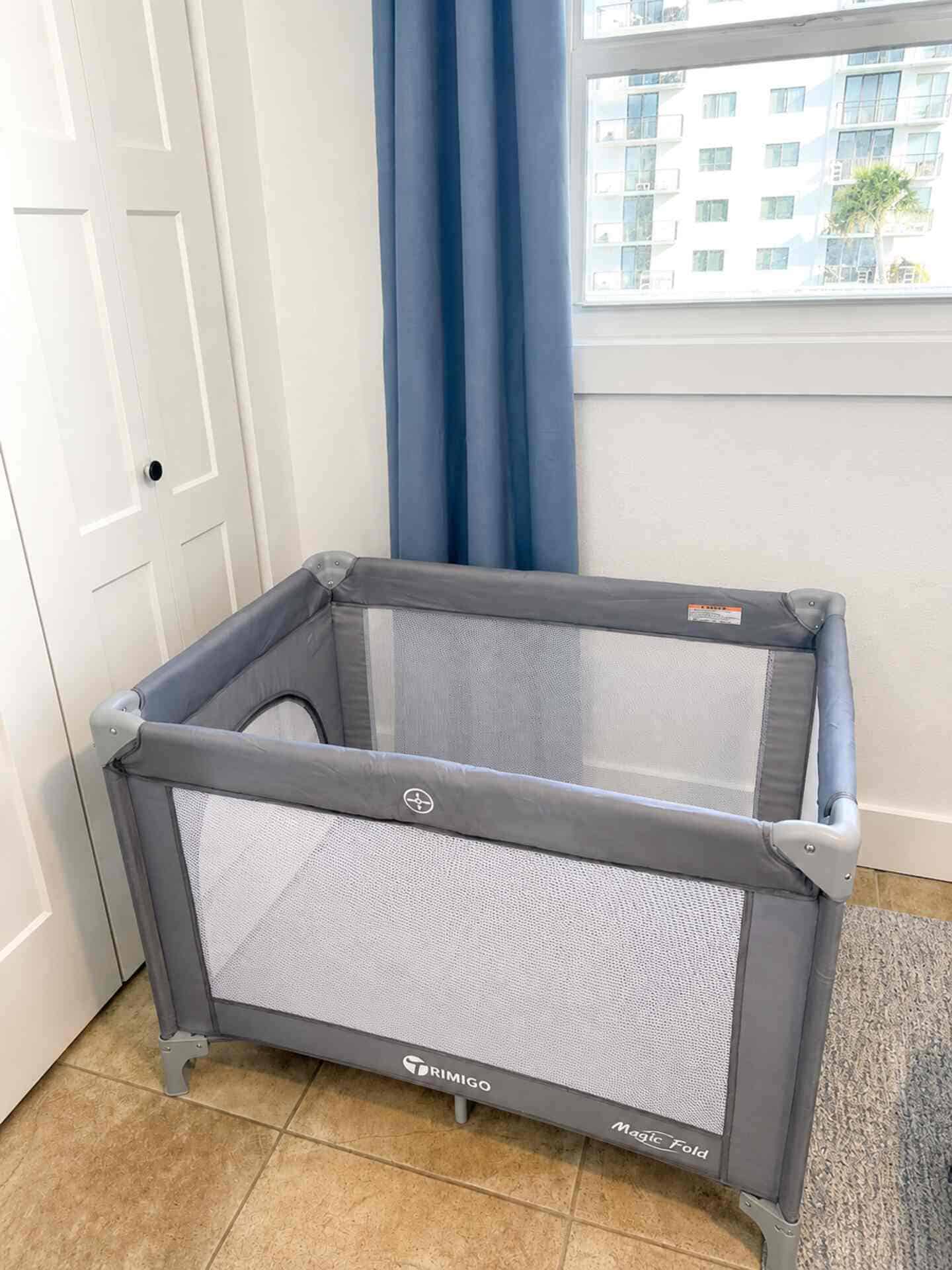 Portable playpen in a room with ocean view window.
